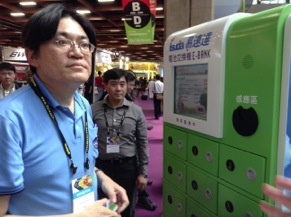 Alex Lee of Kentfa Advanced Technology Corp., demonstrates the company's battery dispenser that allows users to retrieve fully charged vehicle batteries while exchanged an exhausted battery, much like propane gas dispensers in the United States.