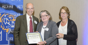Dr. David Arant (left), Chair of the University of Memphis Journalism Department, presents Dr. Sandy Utt (center) with the 2015 D. Mike Pennington Award for Outstanding Mentoring, as Mike Pennington’s widow, Patricia (Patsy) Pennington (right) looks on.